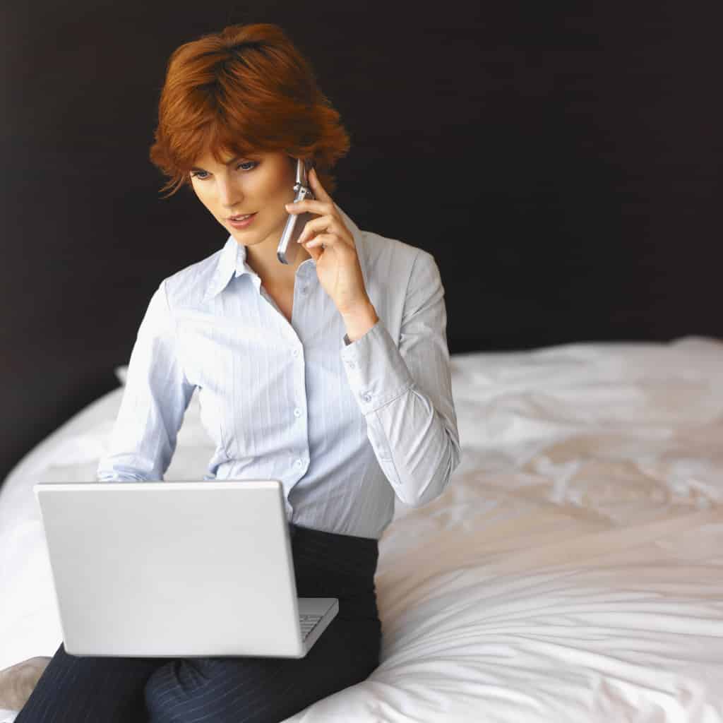 Front view of businesswoman working on laptop and talking on mobile phone