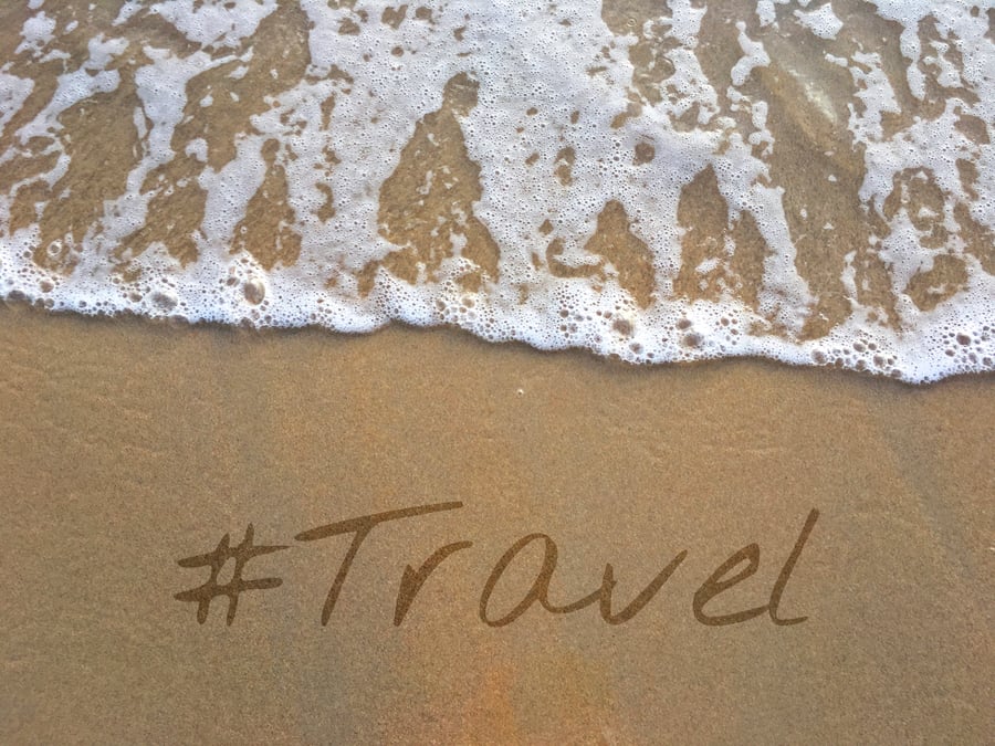 the word travel written in sand on a beach
