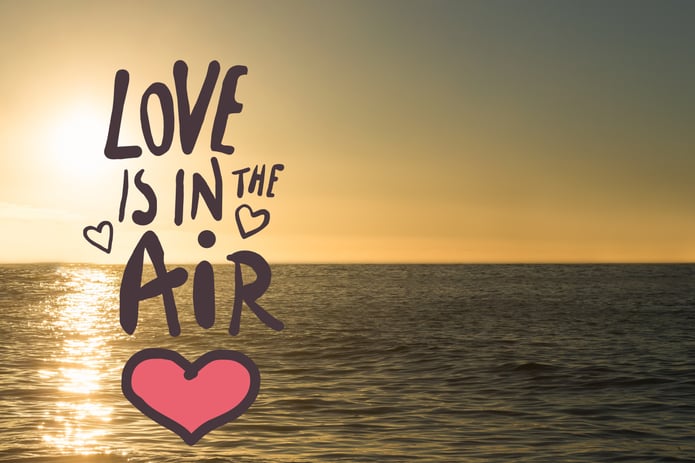 text love is in the air is seen against a sunset